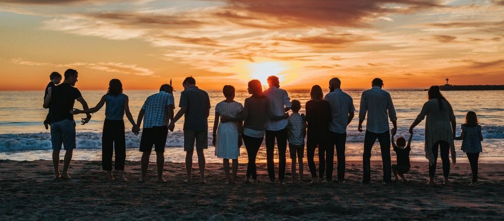 People standing together on a beach at sunset