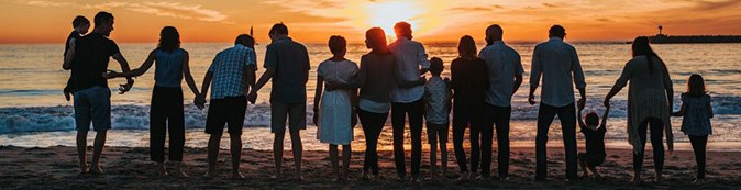 A line of people holding hands on a beach at sunset