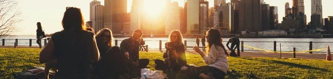 People sitting together in a circle on grass by a city waterfront