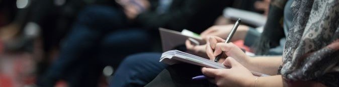 A person taking notes in a notebook during a meeting