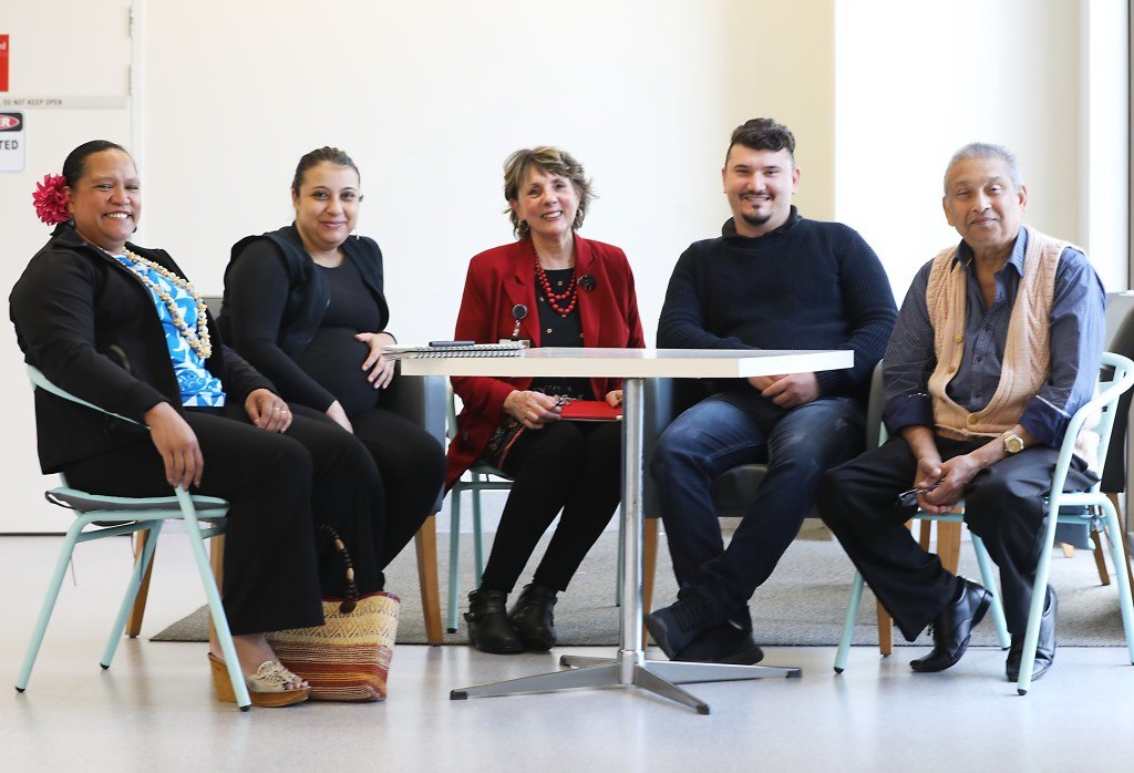 Coralie seated at a table with five community members